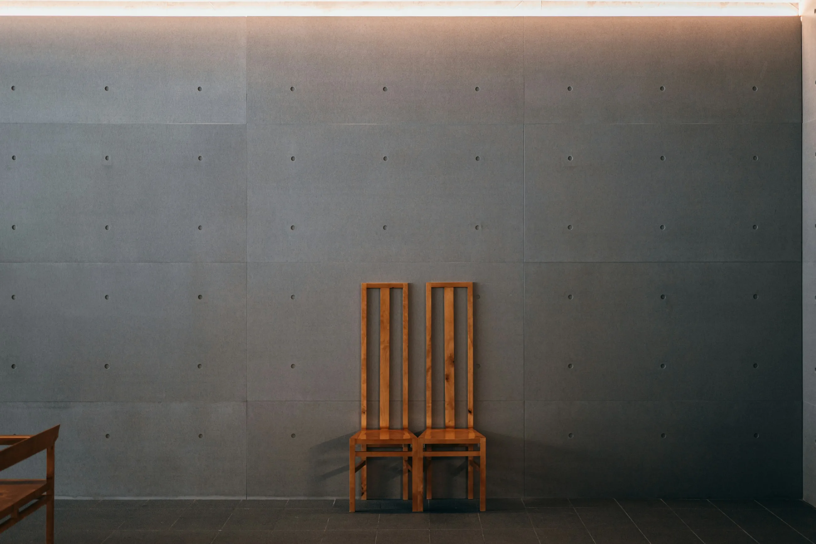 A simple wooden chair beside a plain white wall.